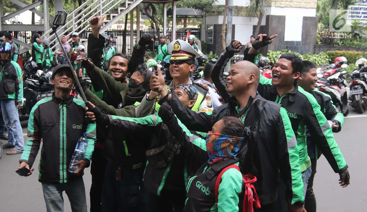 Sejumlah pengemudi ojek online berswafoto dengan polisi saat melakukan aksi di seberang Istana Merdeka, Jakarta, Selasa (27/3). (Liputan6.com/Arya Manggala)