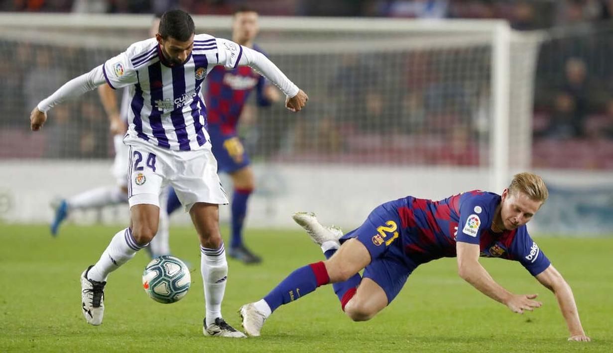 Gelandang Barcelona, Frenkie de Jong, terjatuh saat berebut bola dengan pemain Real Valladolid, Joaquin Fernandez, pada laga La Liga 2019 di Stadion Camp Nou, Selasa (29/10). Barcelona menang 5-1 atas Real Valladolid. (AP/Joan Monfort)