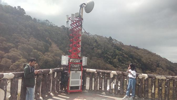 Dua orang pengunjung, nampak tengah menikmati akses jaringan seluler di atas ketinggian 'Menara Pandang', sambil menyaksikan view wisata di kawasan TWA Gunung Papandayan, Garut, Jawa Barat (Liputan6.com/Jayadi Supriadin)