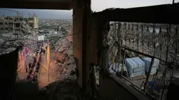Warga Palestina di Gaza terpaksa beribadah di masjid-masjid yang rusak parah atau di antara puing-puing bangunan. Tampak dalam foto, warga Palestina duduk di meja panjang di tengah reruntuhan bangunan yang hancur untuk berbuka puasa bersama, selama bulan suci Ramadan di Khan Younis, Jalur Gaza, Kamis 19 Februari 2026. (AP Photo/Abdel Kareem Hana)
