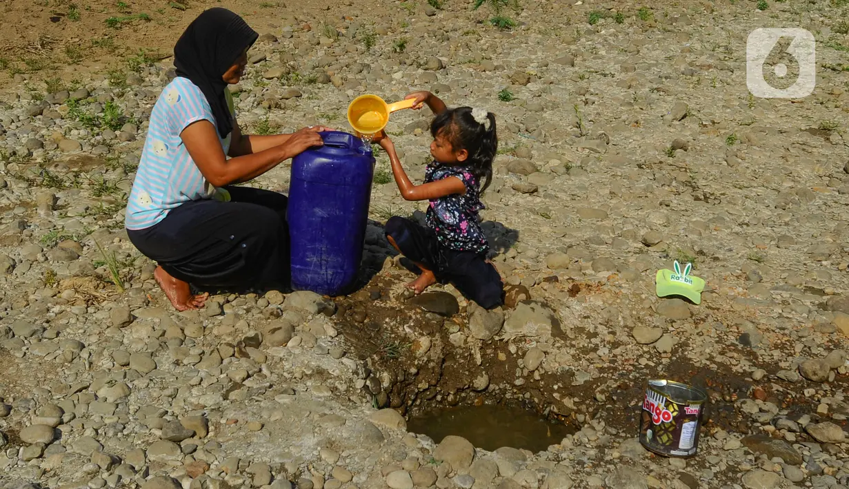Seorang anak bersama ibunya mengambil air pada galian sumur di tengah aliran Sungai Cihoe, Kamis (28/9/2023). Warga Desa Sukagalih, Jonggol, Bogor, mengalami kesulitan air bersih di tengah fenomena El Nino yang menyebabkan musim kemarau berkepanjangan. (merdeka.com/Arie Basuki)