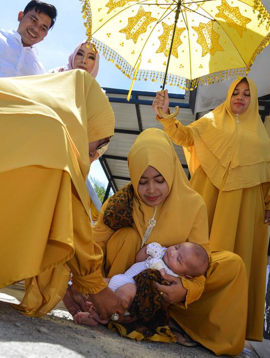 Tokoh adat dan agama menggendong bayi pada ritual 'peutron tanoh aneuk' (turun tanah anak) di Banda Aceh, Aceh, Senin (15/7/2019). Ritual turun tanah anak yang telah menjadi tradisi sakral bagi masyarakat Aceh yang dilaksanakan pada saat bayi berusia 44 hari. (CHAIDEER MAHYUDDIN / AFP)