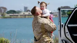 Seorang Angkatan Laut AS memeluk anaknya saat tiba di Camp Pendleton di Oceanside, California, AS, Kamis (11/5). Unit Ekspedisi Kelautan 11  telah menjalani tugas ke sejumlah negara selama 7 bulan. (AFP/ Sandy Huffaker)