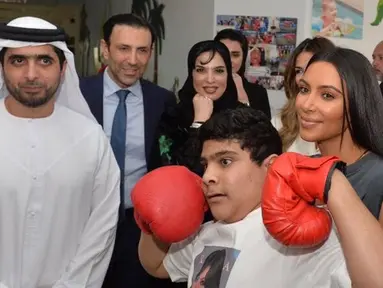 Artis reality TV, Kim Kardashian berpose dengan anak penyandang cacat di Rashid Media Centre, Dubai (16/1). Anak-anak penyandang cacat memberi sambutan khusus dengan tarian tradisional untuk Kim Kardashian. (AFP Photo And Rashid Media Center/Stringer) 