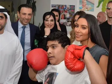 Artis reality TV, Kim Kardashian berpose dengan anak penyandang cacat di Rashid Media Centre, Dubai (16/1). Anak-anak penyandang cacat memberi sambutan khusus dengan tarian tradisional untuk Kim Kardashian. (AFP Photo And Rashid Media Center/Stringer) 