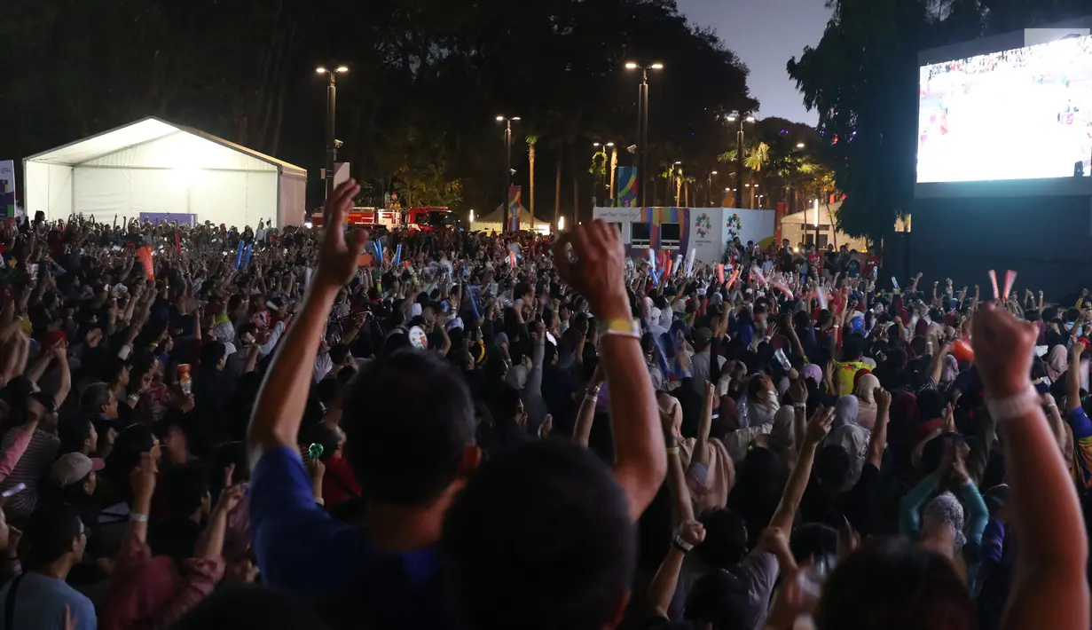 Suporter tim bulutangkis Indonesia bersorak saat menyaksikan siaran langsung laga perempat final dan 16 besar bulutangkis Asian Games 2018 melalui layar lebar di kawasan kompleks GBK, Jakarta, Sabtu (25/8). (Liputan6.com/Helmi Fithriansyah)