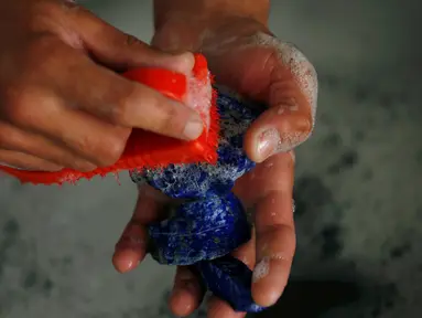  Seorang pria mencuci lapis lazuli di tokonya di Kabul, Afghanistan (5/6/2016). Batu yang dikenal dengan sebutan 'batu surga' ini merupakan batu permata langka yang dihargai sejak zaman kuno karena warna birunya. (REUTERS/Mohammad Ismail)