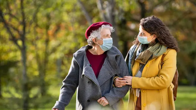 anak perempuan memakai masker membantu ibu berjalan menolong