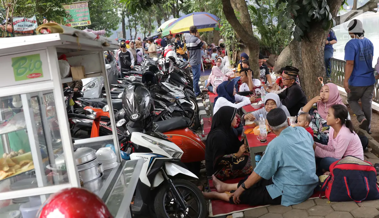 Pengunjung duduk menikmati makanan khas di kawasan Setu Babakan, Jakarta, Minggu (23/6/2019). Ribuan warga memadati kawasan Setu Babakan untuk berwisata dan menyaksikan beragam acara dalam rangka perayaan HUT ke-492 Jakarta. (Liputan6.com/Helmi Fithriansyah)