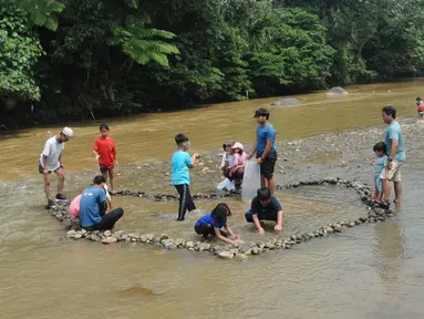 Anak-anak  menangkap ikan pada aliran Sungai Ciliwung di kawasan Bendungan Katulampa, Bogor, Minggu (15/5/2022). Kegiatan bermain sambil mengenalkan alam kawasan daerah aliran sungai (DAS) Ciliwung seperti hiking, menangkap ikan dan rafting yang diadakan oleh Hiking Bocah ini dilakukan setiap akhir pekan dengan biaya Rp 115 ribu/paket anak. (merdeka.com/Arie Basuki)