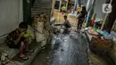 Seorang anak makan saat sejumlah warga bersih-bersih usai banjir di permukiman kawasan Kampung Melayu, Jakarta, Selasa (9/2/2021). Banjir yang berangsur surut dimanfaatkan warga untuk membersihkan rumah dan barang-barang dari endapan lumpur. (Liputan6.com/Faizal Fanani)