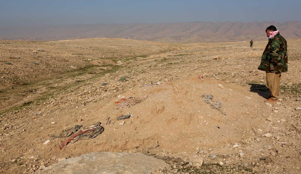 Anggota Kurdi Peshmerga memeriksa sebuah kuburan massal yang diduga lokasi makam anggota Yazidi Irak di pinggiran Sinjar, 30 November 2015. Pasukan Kurdi menemukan kuburan ini usai berhasil merebut kembali kota Irak dari militan ISIS. (Reuters/Ari Jalal)