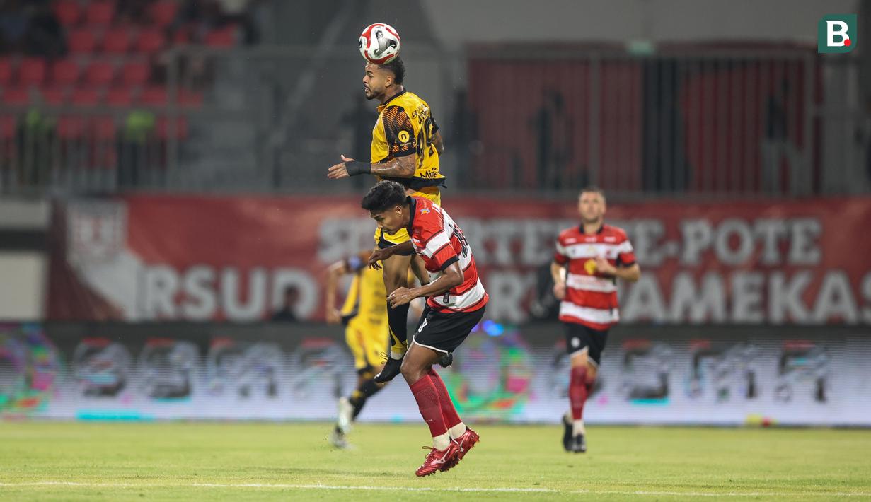 Pemain Persija Jakarta, Emaxwell (atas) berduel dengan pemain Madura United pada lanjutan BRI Super League 2025/2026 di Stadion Gelora Ratu Pamelingan, Jumat (24/10/2025) malam WIB. (Bola.com/Abdul Aziz).