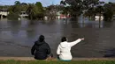 Orang-orang melihat daerah banjir di pinggiran Kota Melbourne, Maribyrnong, Australia, Jumat (14/10/2022). ABC menyebut fenomena di Victoria terjadi sekali tiap 200 tahun sekali. (William WEST/AFP)