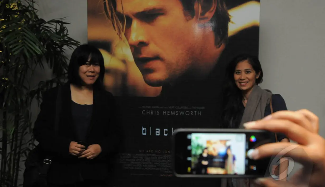 Para penonton berfoto dengan background poster Film Blackhat yang dibintangi Chris Hemsworth saat Premier Film Blackhat di Plaza Indonesia XXI, Jakarta, Selasa (13/01/2015 - Herman Zakaria)