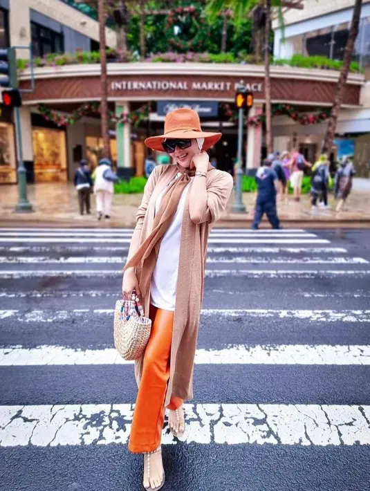 Gaya liburan yang simple tapi chic, padukan cardigan panjang warna cokelat muda dengan t-shirt dan cutbray pants warna orange. (Instagram/princessyahrini).