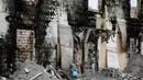 Sebuah patung terlihat di depan bangunan yang hangus terbakar, di desa dekat Kiev, Ukraina, Minggu (29/5). Sedikitnya 17 orang tewas orang tewas setelah kebakaran yang menghanguskan sebuah gedung yang digunakan sebagai panti jompo. (REUTERS/Gleb Garanich)