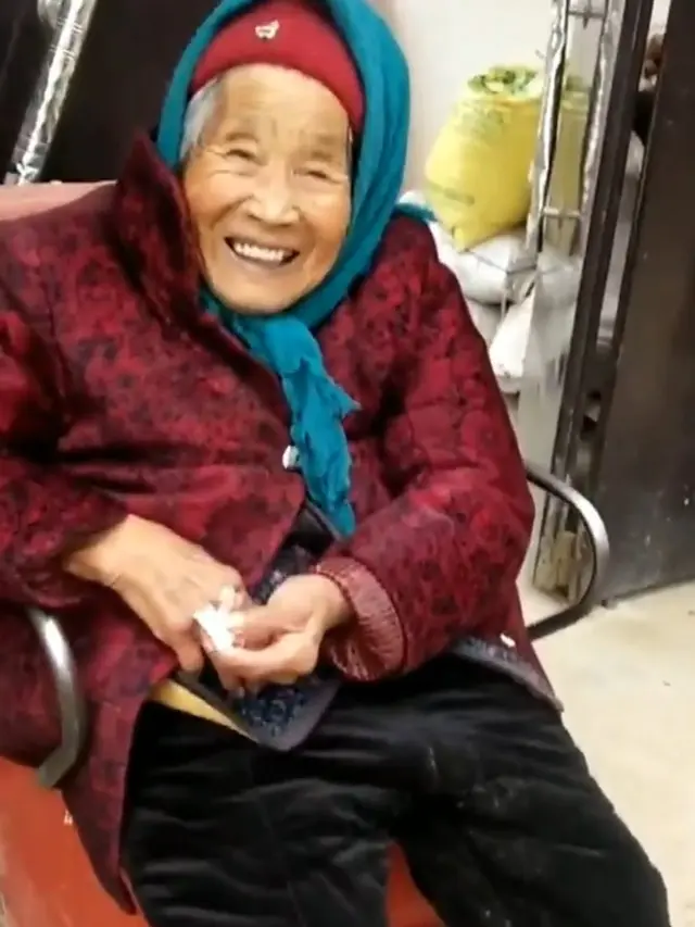 Yang Chengzhi, 84, tersenyum lepas setelah menerima permen dari ibunya. (Source: tangkapan layar dari akun Twitter People's Daily, China)