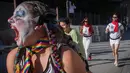 Peserta berdandan seperti badut berlarian selama acara parodi tahunan "Running of the Clowns" di Pasadena, California pada 20 Oktober 2019. Lari dikejar kawanan badut ini merupakan parodi yang mengolok-olok lomba dikejar banteng di Spanyol. (Mark RALSTON / AFP)
