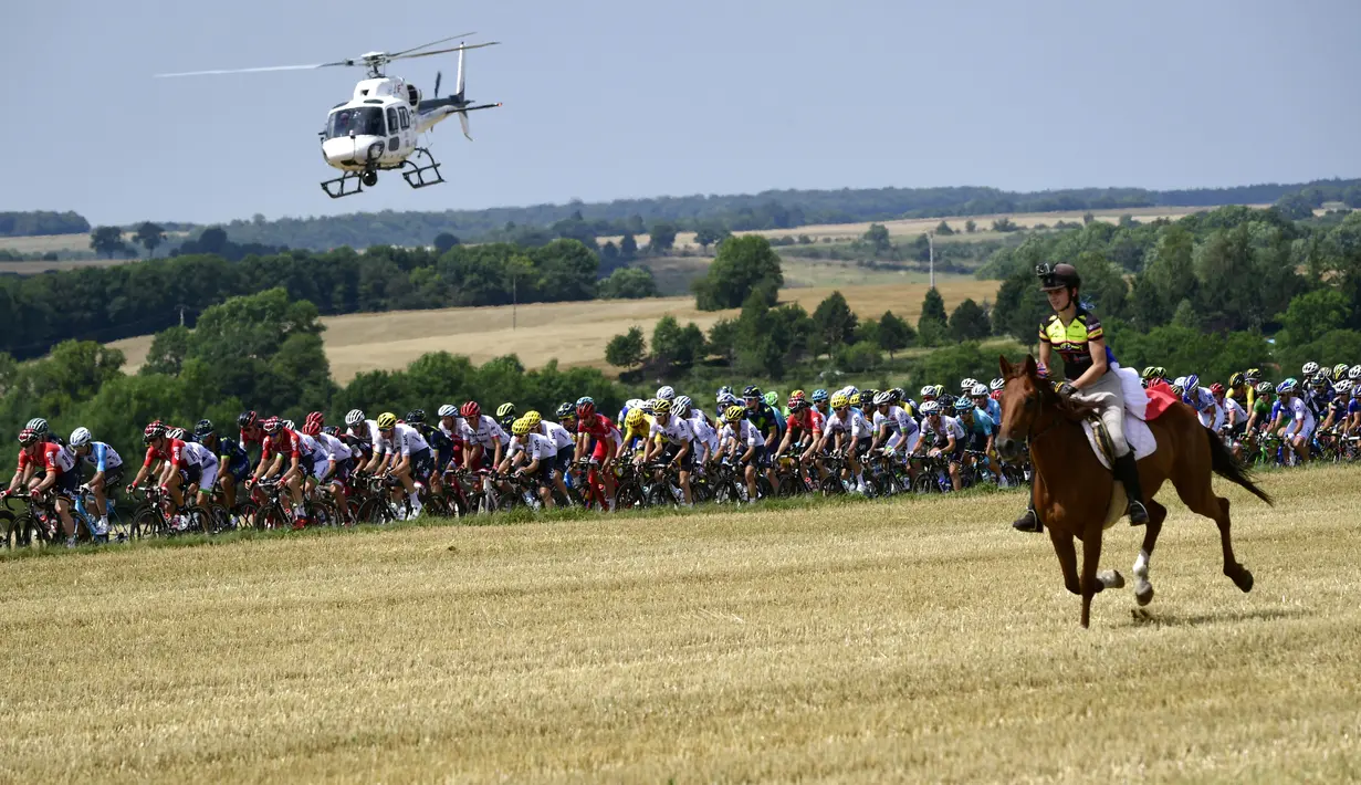 Seorang wanita menunggang kuda mengikuti pebalap  pada etape ketujuh Tour de France yang memiliki jarak tem[puh 213,5 km antara Troyes dan Nuits-Saint-Georges, (7/7/2017). (AFP/Philippe Lopez)