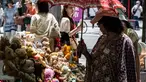 Seorang perempuan (kanan) menggunakan payung untuk berlindung dari teriknya sinar matahari saat melihat-lihat boneka beruang yang dijual di pasar barang antik di pusat kota Tokyo, Jepang, Senin (17/7/2023). (Richard A. Brooks / AFP)