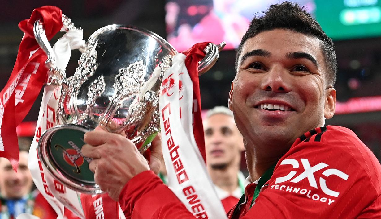 Pemain Manchester United, Casemiro mengangkat trofi setelah memenangkan final Carabao Cup 2023 melawan Newcastle United yang berlangsung di Wembley Stadium, Minggu (26/2/2023) waktu setempat. Casemiro mencetak gol pertama dalam pertandingan ini. (AFP/Adrian Dennis)