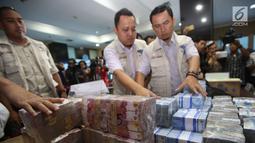 Petugas menata barang bukti hasil tindak pidana pencucian uang (TPPU) kasus narkoba di kantor BNN, Jakarta, Selasa (13/6). Total senilai Rp 39 miliar disita dari empat tersangka yang terkait dengan jaringan Freddy Budiman. (Liputan6.com/Yoppy Renato)