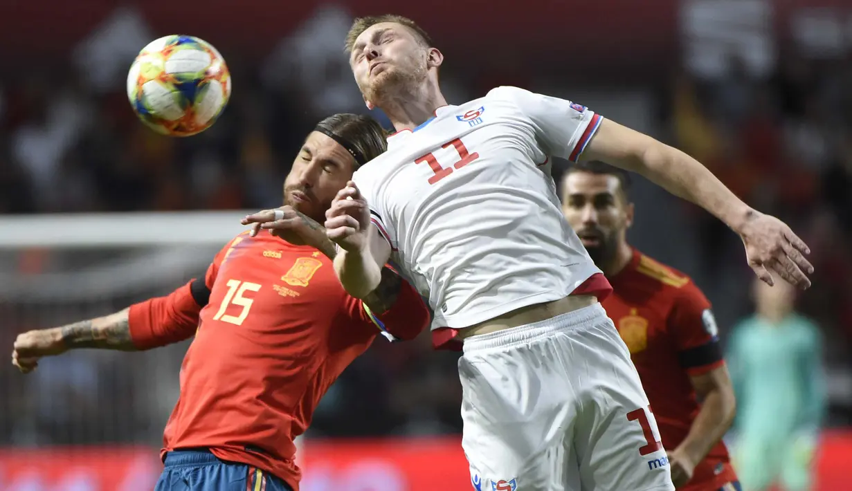 Bek Spanyol, Sergio Ramos, duel udara dengan striker Kepulauan Faroe, Klaemint Olsen, pada laga Kualifikasi Piala Eropa 2020 di Stadion El Molinon, Gijon, Minggu (8/9). Spanyol menang 4-0 atas Kepulauan Faroe. (AFP/Miguel Riopa)