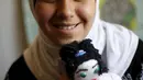 Omayma bersama boneka kesayangannya tersenyum di rumahnya di kamp pengungsi Al Zaatari, Mafraq, Yordania (21/4). Meski berusia 14 tahun, Omayma sangat aktif menyerukan perlawanan terhadap pernikahan dini yang marak di Suriah. (REUTERS / Muhammad Hamed)