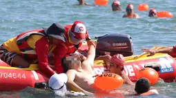 Seorang perenang diangkat dari air dalam keadaan tidak sadar oleh petugas penyelamat ketika mengikuti lomba renang lintas pelabuhan berjarak 1.500 meter di Hong Kong, Minggu (16/10). Perenang itu tewas saat dilarikan ke rumah sakit. (REUTERS/APPLE DAILY)