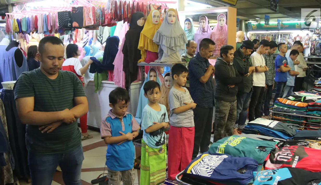 Sejumlah umat muslim melaksanakan salat jumat pada bulan Ramadan di antara pakaian yang dijajakan di kios Pasar Tanah Abang, Jakarta, Jumat (25/5). Jemaah terpaksa melakukan salat di lorong kios karena terbatasnya ruang masjid (Liputan6.com/Arya Manggala)
