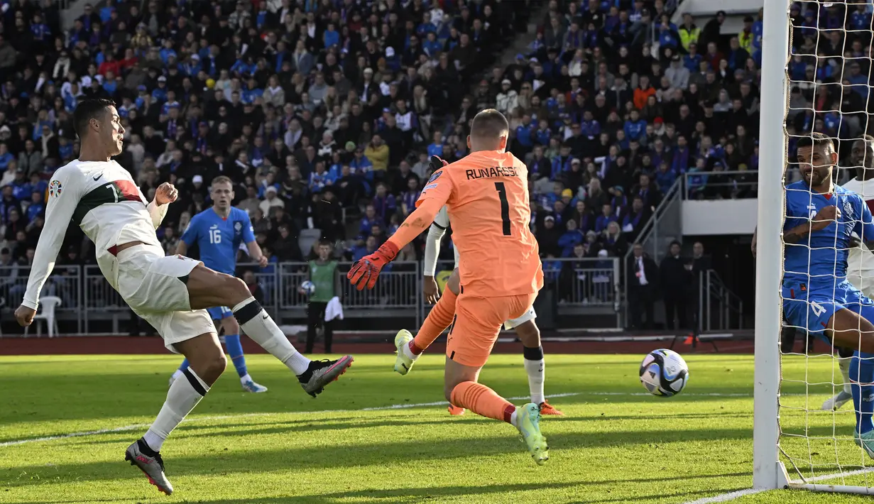 Pemain Timnas Portugal, Cristiano Ronaldo (kiri), menendang bola ke gawang Timnas Islandia yang membuahkan gol dalam pertandingan lanjutan grup J Kualifikasi Euro 2024 yang berlangsung di Laugardalsvollur, Reykjavik, Rabu (21/6/2023) dini hari WIB. Ini merupakan gol ke-123 Ronaldo bersama Portugal. (AFP/Halldor Kolbeins)
