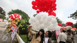 Ekspresi warga yang berfoto dengan latar belakang balon berwarna merah putih yang menghiasi halaman Balai Kota, Jakarta, Senin (8/5). Ribuan balon yang berwarna merah putih ini meramaikan kemeriahan di Balai Kota. (Liputan6.com/Faizal Fanani)