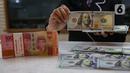 Aktivitas karyawan saat menunjukkan uang rupiah dan dolar AS di salah satu tempat penukaran mata uang asing di Jakarta, Senin (13/1/2025). (Liputan6.com/Angga Yuniar)