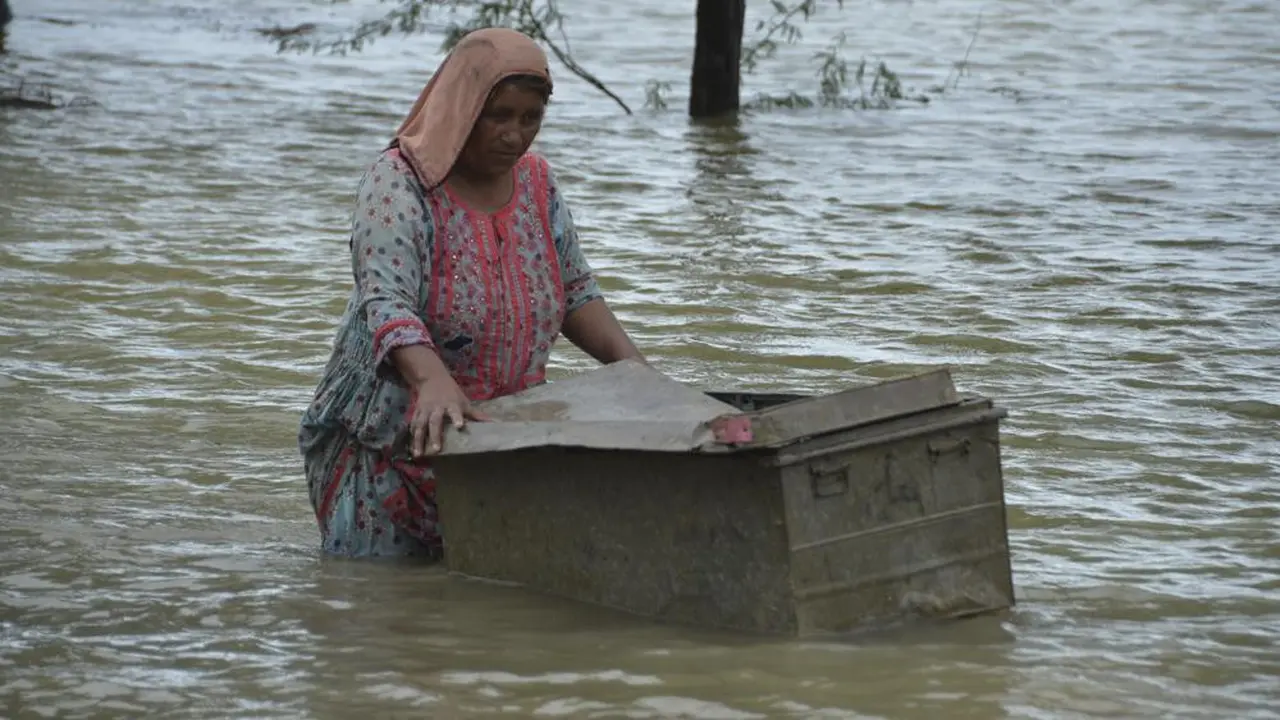 Seorang wanita yang menjadi korban banjir di Pakistan berusaha menyelematkan harta bendanya.