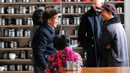 Orang-orang berbincang di depan rak peralatan makan di sebuah kantin untuk warga lanjut usia (lansia) di Desa Yingshan, Kota Quanzhou, Provinsi Fujian, China pada 17 Desember 2020. Kantin lansia dikelola menggunakan donasi lokal, dengan para warga lokal yang menjadi sukarelawan. (Xinhua/Wei Peiquan