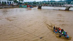 Jembatan ini merupakan jalur utama penghubung Bireuen dengan Bener Meriah dan Aceh Tengah. Tampak foto menunjukkan pemandangan udara warga yang menyeberangi sungai dengan perahu setelah jembatan rusak akibat banjir di Juli, provinsi Aceh, pada Minggu 14 Desember 2025. (CHAIDEER MAHYUDDIN/AFP)