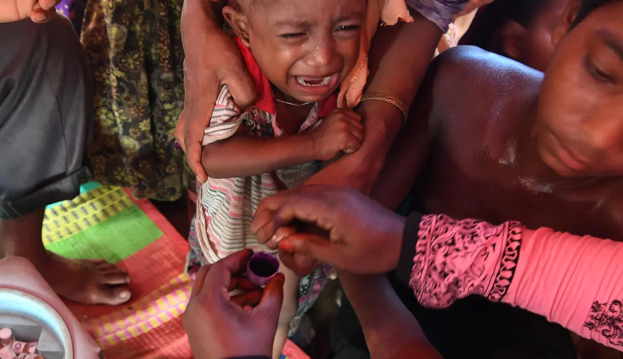 Seorang anak menangis saat diberi vaksin kolera di kamp pengungsi Thankhali di distrik Ukhia (10/10). Di tengah kekhawatiran wabah, PBB memberikan vaksinasi kolera untuk ampir satu juta orang Rohingya. (AFP Photo/Indranil Mukherjee)
