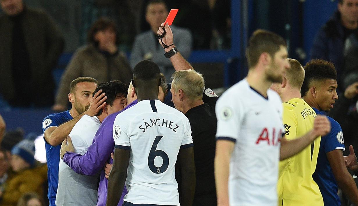 Penyerang Tottenham Hotspur, Son Heung-min, mendapat kartu merah usai melakukan pelanggaran terhadap gelandang Everton, Andre Gomes, pada laga Premier League di Goodison Park, Minggu (3/11). Tekel tersebut menyebabkan Gomes mengalami patah kaki. (AFP/Oli Scarff)