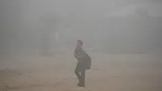 Seorang anak sekolah India melewati jalan di New Delhi yang diselimuti kabut asap, Rabu (8/11). Kabut asap tebal akibat polusi udara yang parah menyebabkan aktivitas di pusat kota New Delhi lumpuh seketika. (SAJJAD HUSSAIN/AFP)