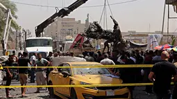 Petugas mengevakuasi bangkai mobil bekas ledakan serangan bom di Baghdad, Irak (30/5). Serangan bom ini meledak di dekat sebuah toko es krim populer di Kota Baghdad. (AP Photo / Karim Kadim)