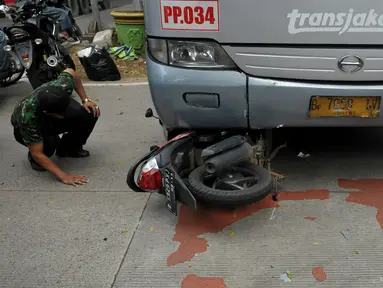 Bus Transjakarta bernomer polisi B 7058 IV menabrak pengendara sepeda motor di kawasan permata hijau, Jakarta, Jumat (27/3/2015). Sejumlah warga sedang melakukan evakuasi speda motor yang berada di dalam bus transjakarta. (Liputan6.com/Johan Tallo)