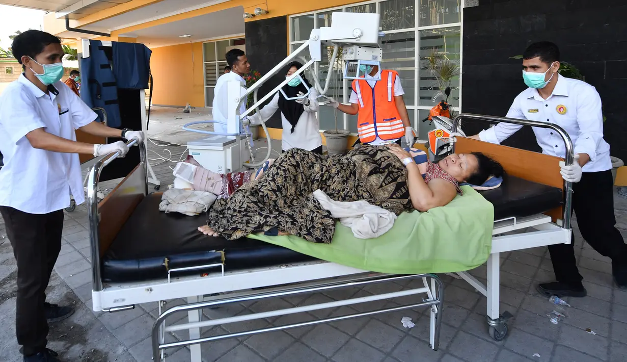 Seorang ibu korban gempa Lombok menjalani perawatan di luar Rumah sakit Moh. Ruslan di Mataram,  Senin (6/8). Berdasarkan laporan sementara yang diterima BPBD NTB, korban meninggal akibat gempa Lombok sudah mencapai 89 orang. (AFP/ADEK BERRY)