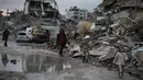 Sementara itu, Badan Perserikatan Bangsa Bangsa (PBB) untuk Pengungsi Palestina (UNRWA) menyebut sedikitnya 93 persen tenda pengungsian tidak layak untuk berlindung, dan semakin buruk kondisinya karena cuaca ekstrim. Tampak dalam foto, warga Palestina berjalan melewati reruntuhan di tengah cuaca buruk Kota Gaza, Kamis 11 Desember 2025. (AP Photo/Jehad Alshrafi)