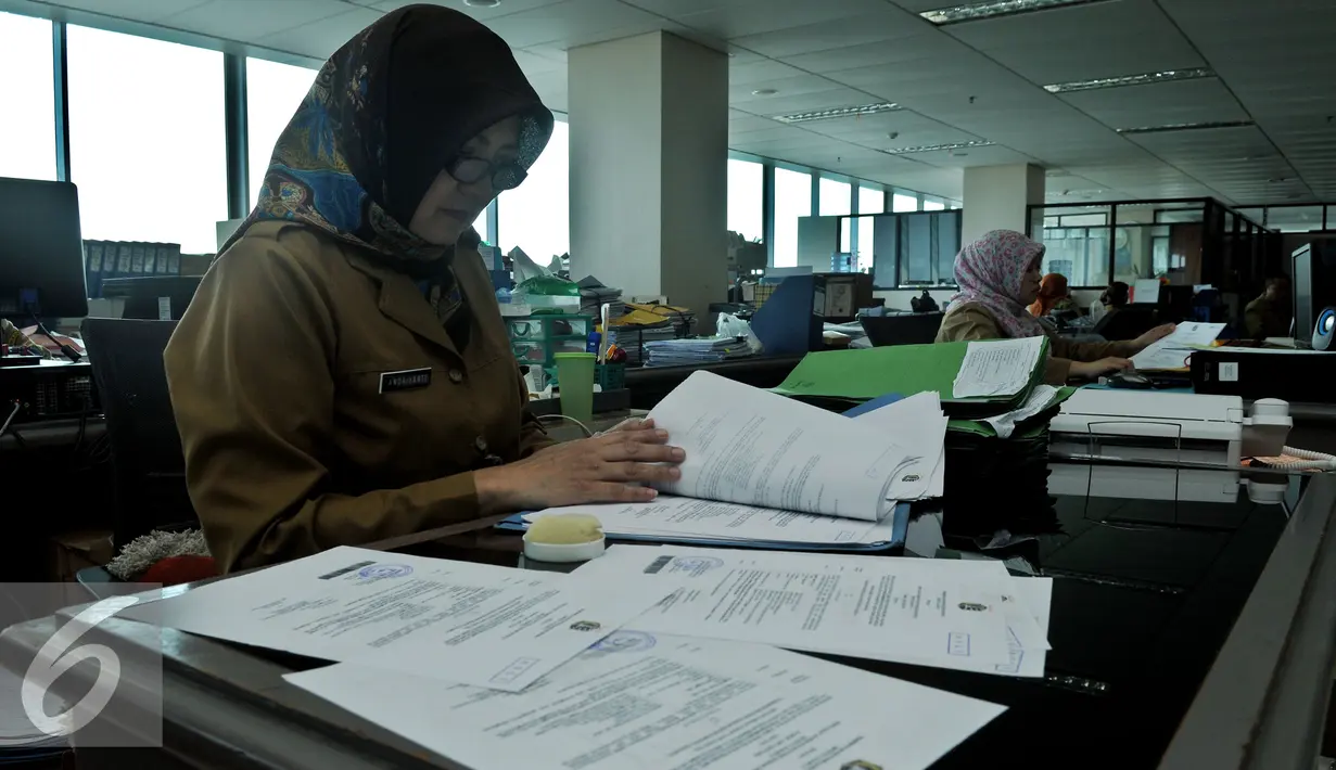 Seorang PNS saat membaca dokumen di kantor Balai Kota DKI, Jakarta, Rabu (22/7/2015). Hari ini adalah hari pertama masuk kerja di lingkungan Pemerintah Daerah Jakarta pasca cuti bersama Idul Fitri 1436H. (Liputan6.com/Johan Tallo)