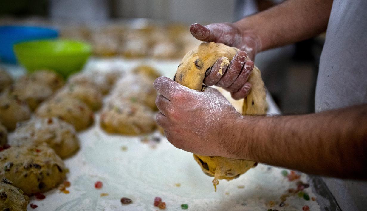 Seorang tukang roti membentuk adonan untuk membuat Bolo Rei atau Kue Raja di toko roti Padaria da Ne, Amadora, Portugal, 16 Desember 2022. Untuk tahun ini, pemenang Bolo Rei terbaik di Portugal adalah sebuah toko roti kecil di Damaia, Amadora. (CARLOS COSTA/AFP)