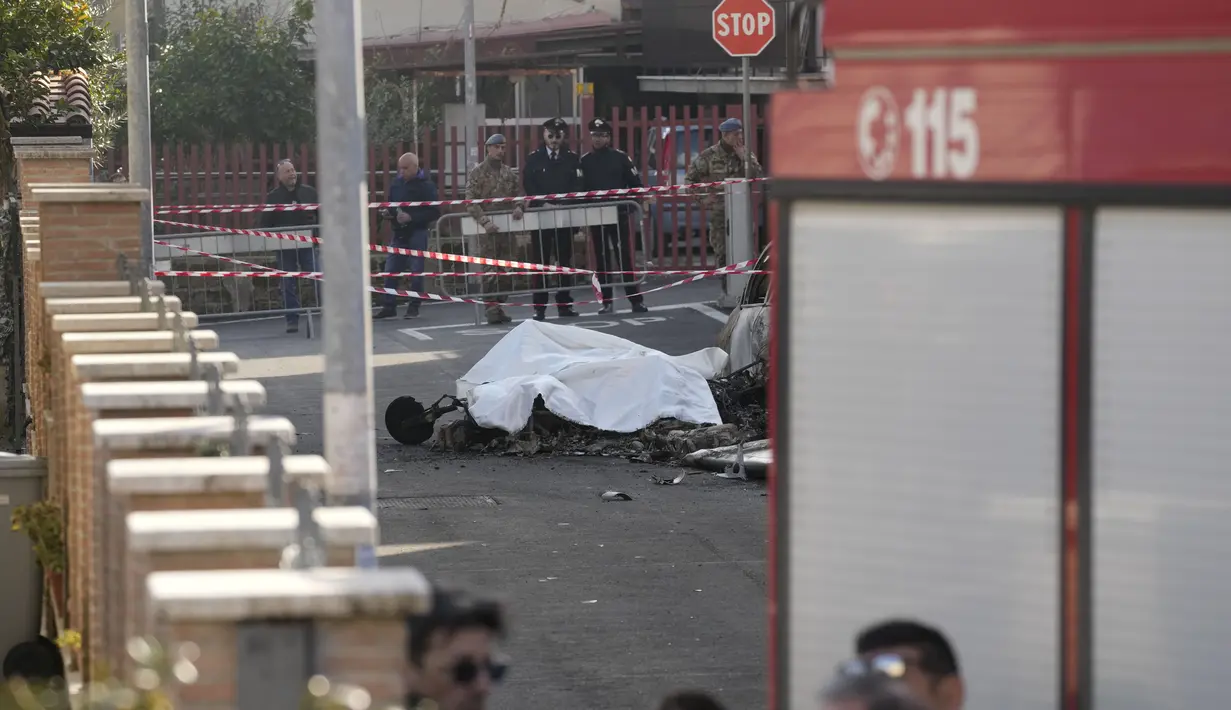 Sisa-sisa yang terbakar salah satu dari dua pesawat U-208 Angkatan Udara Italia yang jatuh ditutup dengan kain putih di distrik pemukiman tempat jatuhnya, di Guidonia, di pinggiran Roma, Selasa (7/3/2023). Dua pesawat U-208 itu sedang dalam penerbangan latihan rutin di atas ibukota Italia saat saat mereka mengalami kecelakaan itu. (AP Photo/Andrew Medichini)