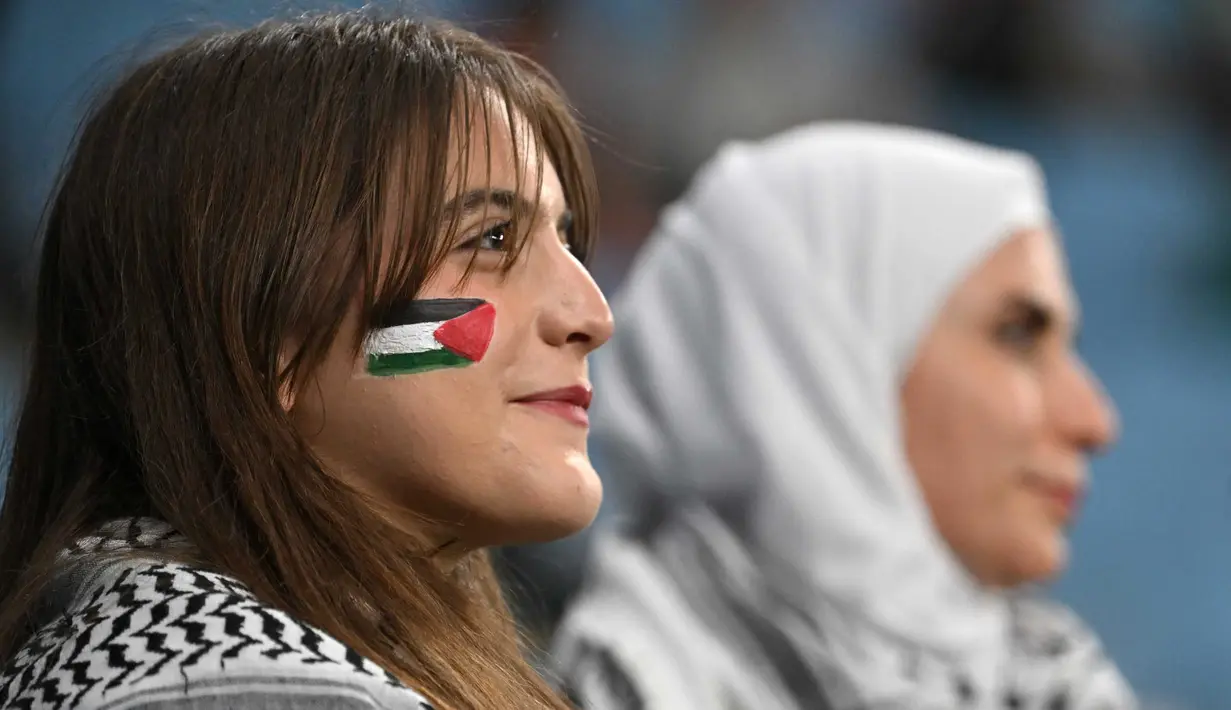 Seorang pendukung mengenakan cat wajah terlihat sebelum dimulainya pertandingan sepak bola Grup C Piala Asia AFC Qatar 2023 antara Palestina dan Uni Emirat Arab di Stadion Al-Janoub di Al-Wakrah, Doha pada 18 Januari 2024. (HECTOR RETAMAL/AFP)