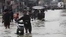 Sejumlah pengendara motor dan warga terpaksa menerobos banjir menggunakan gerobak yang disewakan warga sekitar. (Liputan6.com/Angga Yuniar)