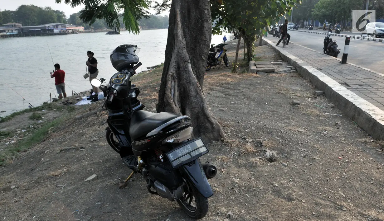 Sepeda motor terparkir di bawah pohon di Danau Sunter, Jakarta, Senin (22/7/2019). Tidak adanya fasilitas parkir di kawasan tersebut menyebabkan pengunjung Danau Sunter memarkirkan sepeda motor mereka di sepanjang trotoar sehingga mengganggu akses pejalan kaki. (merdeka.com/Iqbal Nugroho)